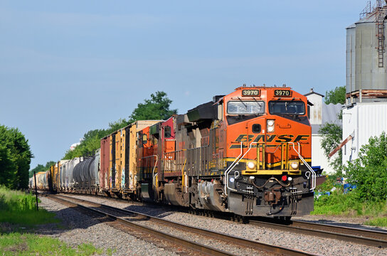 Multple locomotives lead a Burlington Northern Santa Fe merchandise freight train westbound through a small Illinois community on its journey outbound from Chicago.