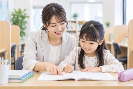 塾で教える女性講師と宿題をする小学生