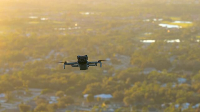 Drone hovering above modern suburban homes, filming panoramic aerial view for real estate marketing and property inspection purposes.