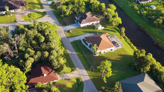Flood water canal in North Port residential community with private homes, green yards and organized streets, capturing suburban sprawl, wealth, and housing market growth in the USA.