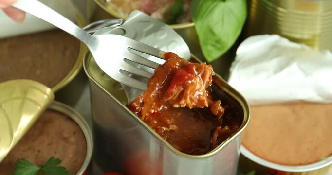 Woman eating canned meat with fork at table, closeup