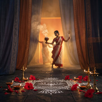 Traditional bengali women entering illuminated temple with smoking dhunuchi and ritual lamps during durga puja and navratri evening worship ceremony together indoors