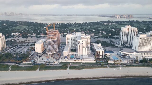 Aerial glide past a beachfront tower under construction in miami
