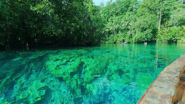 Boat navigating crystal clear turquoise water in Paisu Pok lake, Banggai