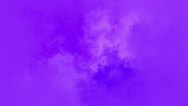 Seamless looping abstract animation of soft amorphous purple and magenta cloud like formations slowly drifting and morphing with grainy diffuse texture against a solid vibrant violet background