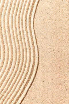 Abstract sand pattern with parallel lines creating a wave-like design on a sandy surface.