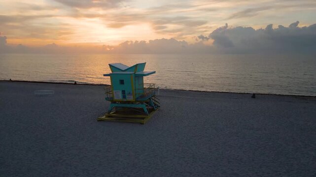 Aerial descent toward a solitary lifeguard tower at miami dawn