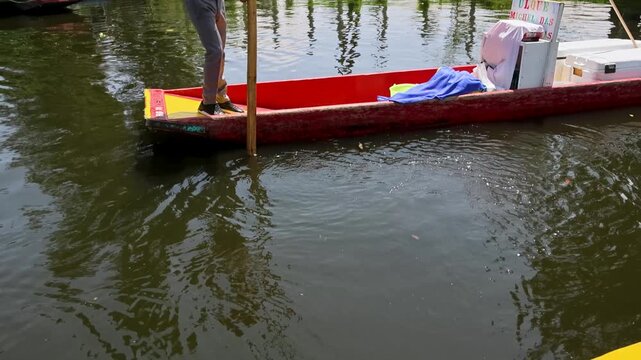Person Steering Mexican Trajinera Boat with Pole on Xochimilco Canal Mexico City