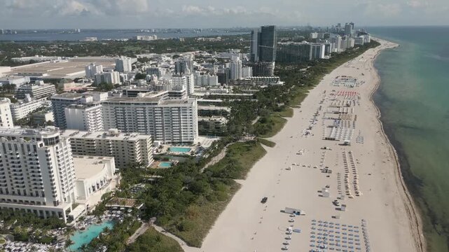 Aerial glide along a sunlit miami beach coastline lined with towers