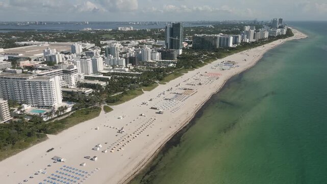 Aerial sweep along the sunlit shoreline of miami beach and collins avenue