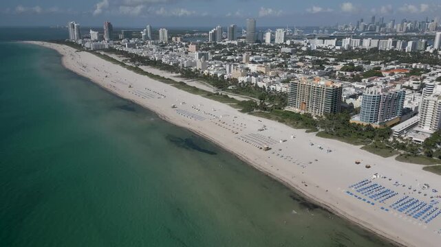 Aerial drift along the emerald shoreline of miami beach and its skyline