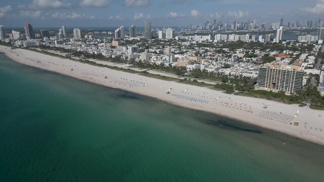Aerial cruise over miami beach shoreline framed by turquoise water and towers