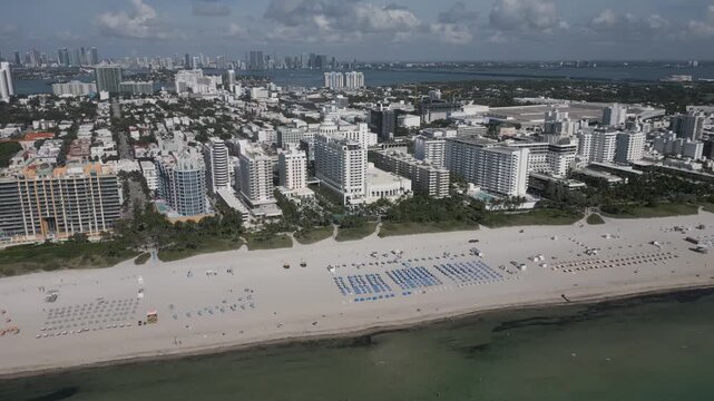 Aerial pass over miami beach hotels lining a sunlit shoreline