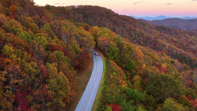 Scenic drive through Tennessee Appalachians in fall season. Car traveling on curvy forest road under vibrant autumn foliage.