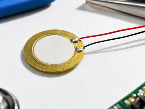Piezoelectric energy harvesting disc with fine leads on a bright workbench in natural daylight