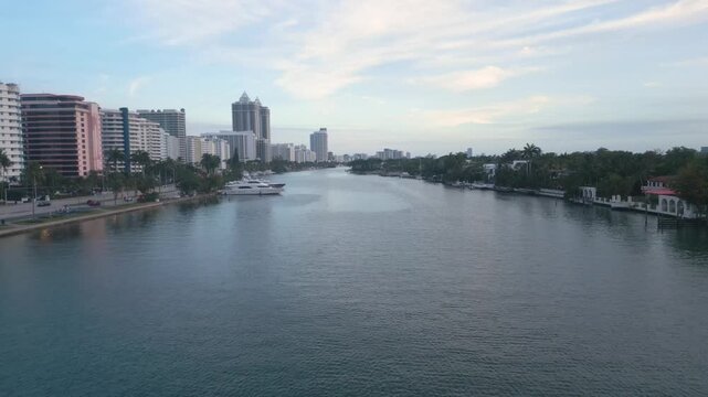 Aerial cruise along a calm miami beach intracoastal channel lined with towers and yachts