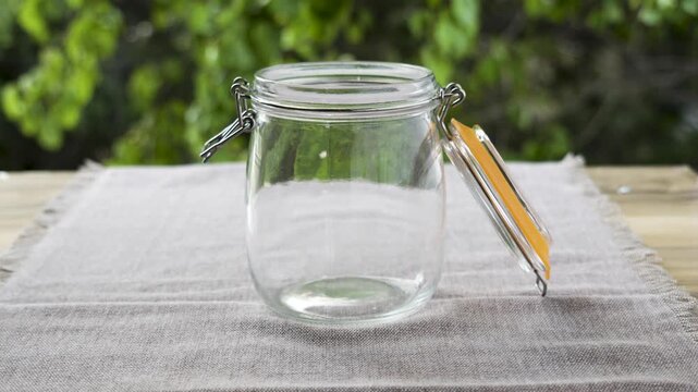 White round rice filling half glass jar on wooden table with waving leaves background, 4K