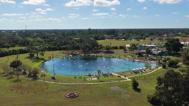 Tourists bathing in Warm Mineral Springs in North Port under bright sunlight, enjoying calm water, outdoor leisure and therapeutic wellness experiences in Florida resort setting.