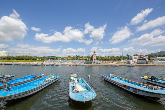 Blue fishing boats moored in a harbor under a summer sky