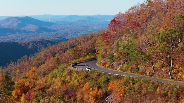 Vehicle parked at mountain viewpoint on the Blue Ridge Parkway in North Carolina. Spectacular fall foliage covers surrounding landscape.