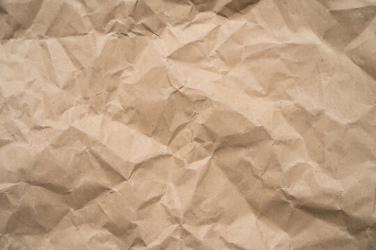 Crumpled brown paper texture with natural wrinkles, folds and vintage kraft surface, ideal as an abstract background for packaging design posters wallpaper and creative projects.
