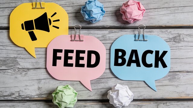 Colorful paper speech bubbles with FEEDBACK text and crumpled paper balls on wooden background