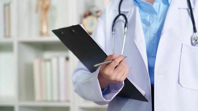 Cropped doctor holding clipboard and pen for medical report in clinic