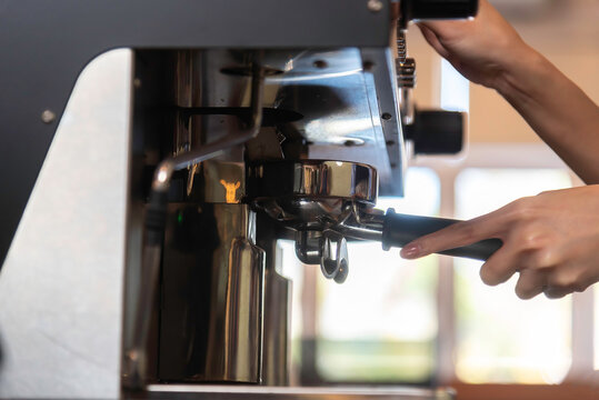 Coffee grinder grinds fresh coffee beans into a portafilter for espresso machine. Barista grind coffee bean with grinder machine.