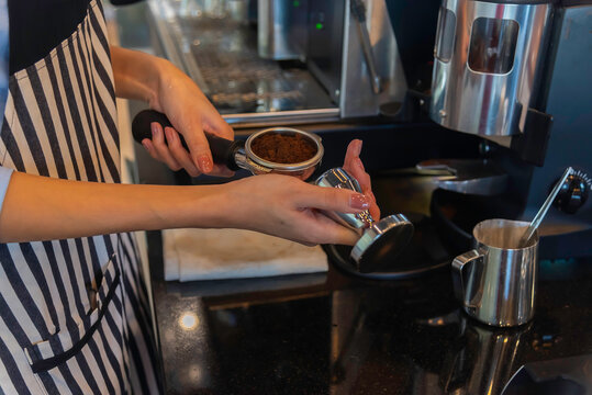 Coffee grinder grinds fresh coffee beans into a portafilter for espresso machine. Barista grind coffee bean with grinder machine.