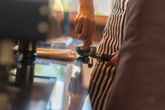 Coffee grinder grinds fresh coffee beans into a portafilter for espresso machine. Barista grind coffee bean with grinder machine.