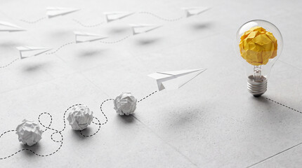 Fototapeta premium Conceptual business innovation and creativity concept with a yellow paper light bulb as a bright idea symbol and white paper planes representing the journey from failed attempts to success.