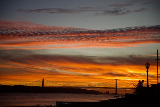 Colorful sunset over 25 de Abril Bridge and Cristo Rei across the Tagus River in Lisbon, Portugal