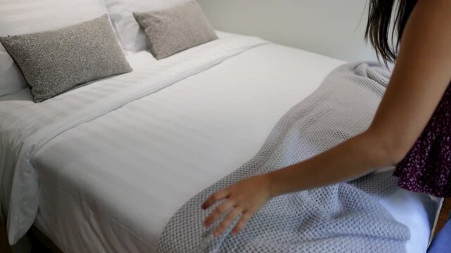 Woman Making Bed by Smoothing Blanket in Hotel Bedroom