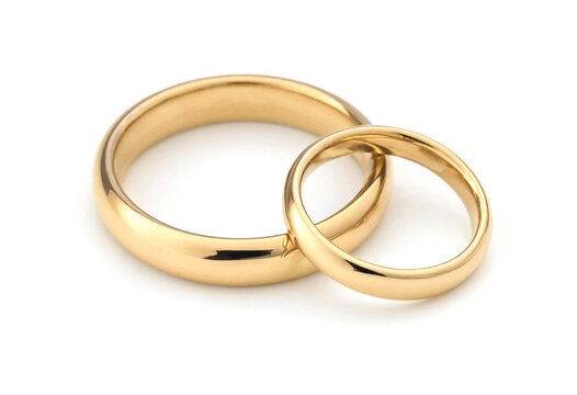 Two golden wedding rings placed next to each other on light surface