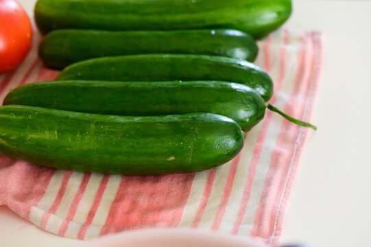 Fresh cucumbers arranged on a pink striped kitchen towel, ready for a delicious summer salad prepara