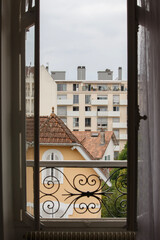 Obraz premium Point Of View Overlooking French House and Apartment Building From Tall Open Window With Balconet