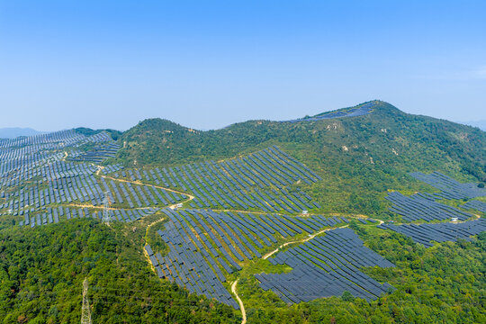 Mountain photovoltaic power station covering green hills with solar panels arrayed on slopes
