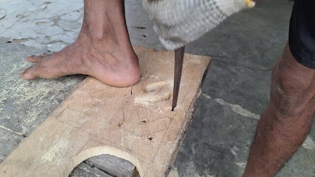 Craftsman cutting letter patterns on wooden board using hand saw and woodworking tools in carpentry workshop