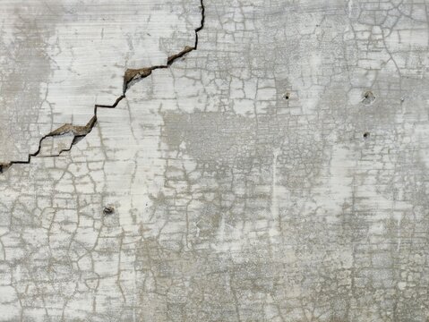 Aged concrete wall showing deep crack and intricate surface texture, ideal as a gritty background with ample copy space for design.