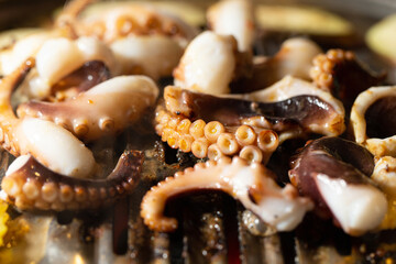 Grilling spicy octopus on hot charcoal BBQ grill netting with smoke © mnimage