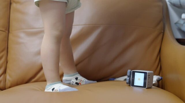Close-up of toddler feet beside AI voice assistant robot on sofa