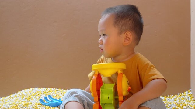 Half-length view of toddler playing with toy excavator in indoor play area