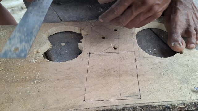 Close up of a craftsman drawing layout pattern on a wooden board using ruler and pencil in a carpentry workshop