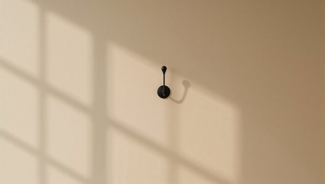 Generative AI a black coat hook on a beige wall casting shadows with sunlight