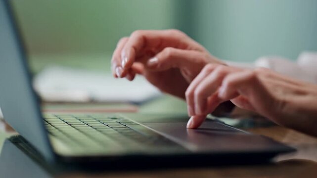 Close up of person hands typing on laptop keyboard in home office.
