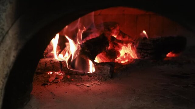 Kitchen fireplace. Traditional oven. Firewood burning in old arch brick stove. Bright red orange roaring flame on dark black logs.