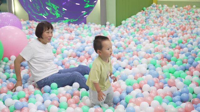 Full-length view of grandmother and toddler playing in ball pit