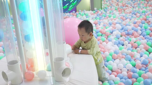 Full-length view of toddler playing with illuminated tubes in ball pit