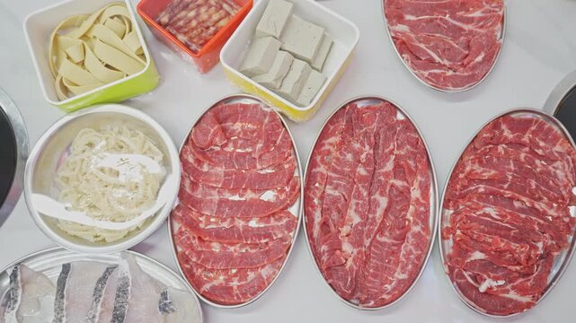 Overhead view of raw beef and ingredients for Chinese hot pot