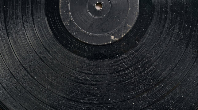 Close up of a vintage black vinyl record with visible dust and surface scratches on the grooves
